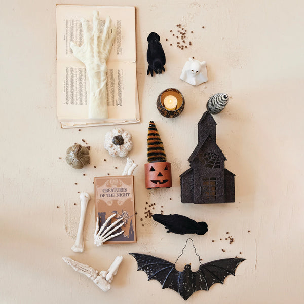 Halloween-themed decorations including a book, candles, and bats on a textured surface.