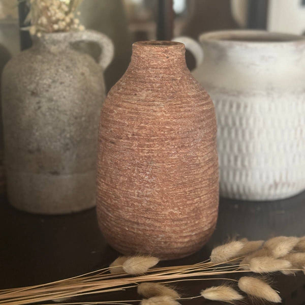 Textured ceramic vases on a dark surface with dried plants