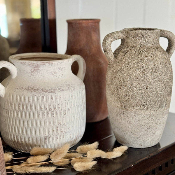 Three ceramic vases on a surface with a blurred background