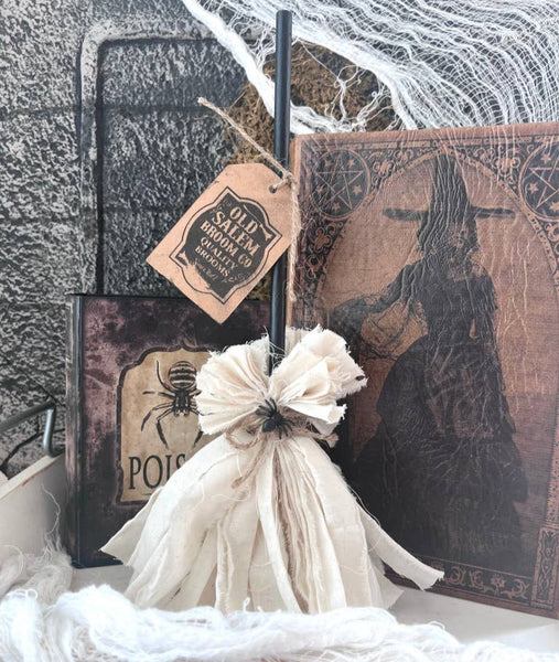 A rustic, primitive witch broom with a tag that reads 'OLD SALT' and 'WITCH BROOM'.