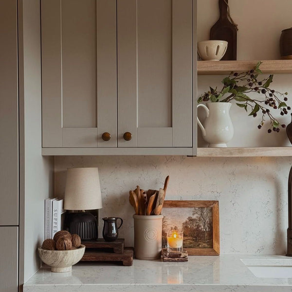 Kitchen counter with decorative items and a lamp, featuring neutral tones.