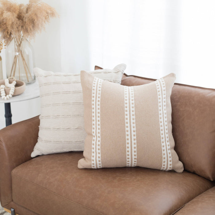 Cream and taupe throw pillows on a leather couch