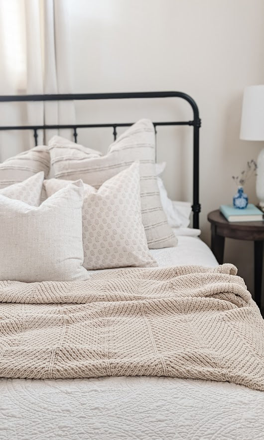 Bed with coordinated, neutral pillow cover sets.