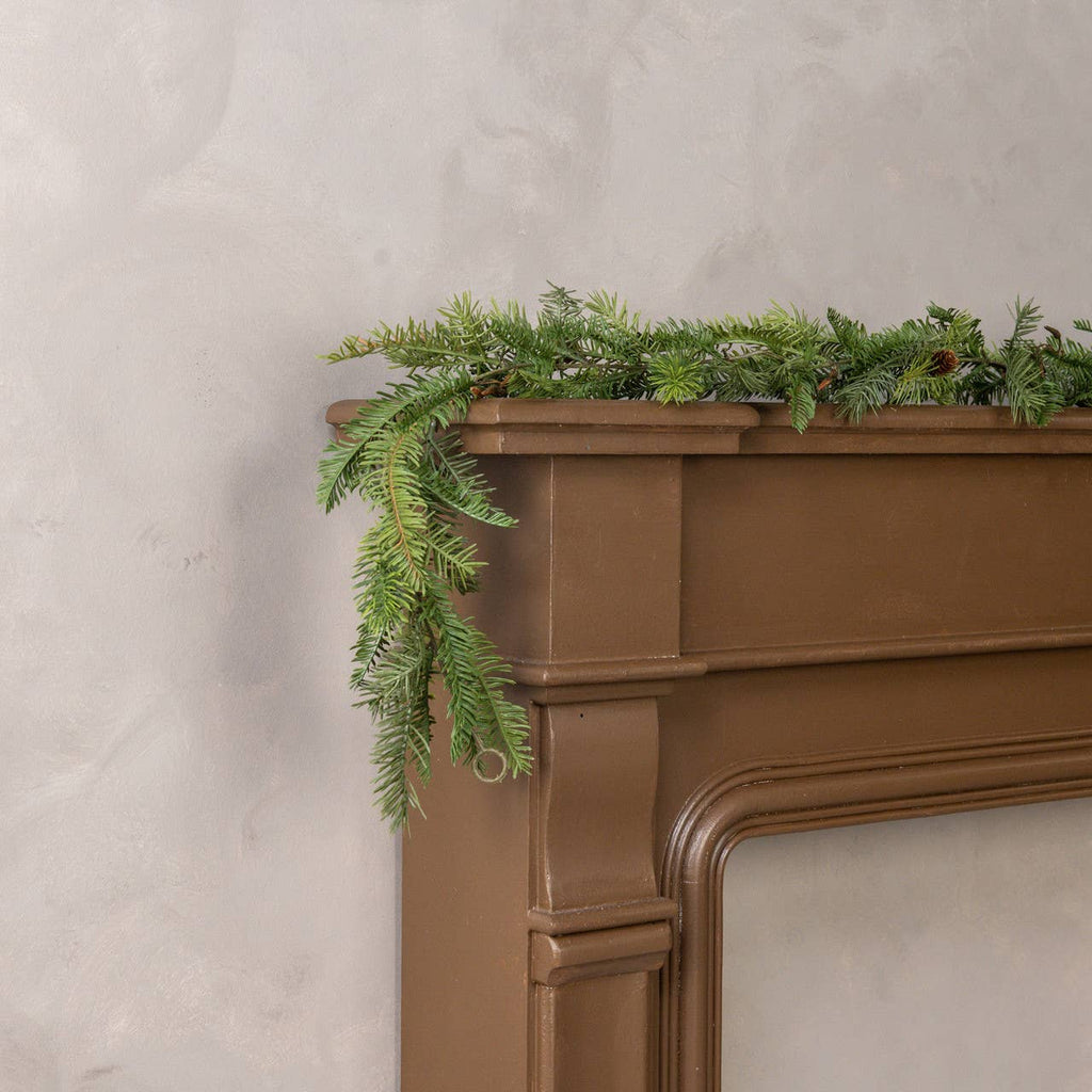 Brown fireplace mantle with faux garland against a beige wall