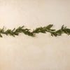 Green artificial Christmas garland on a textured beige background