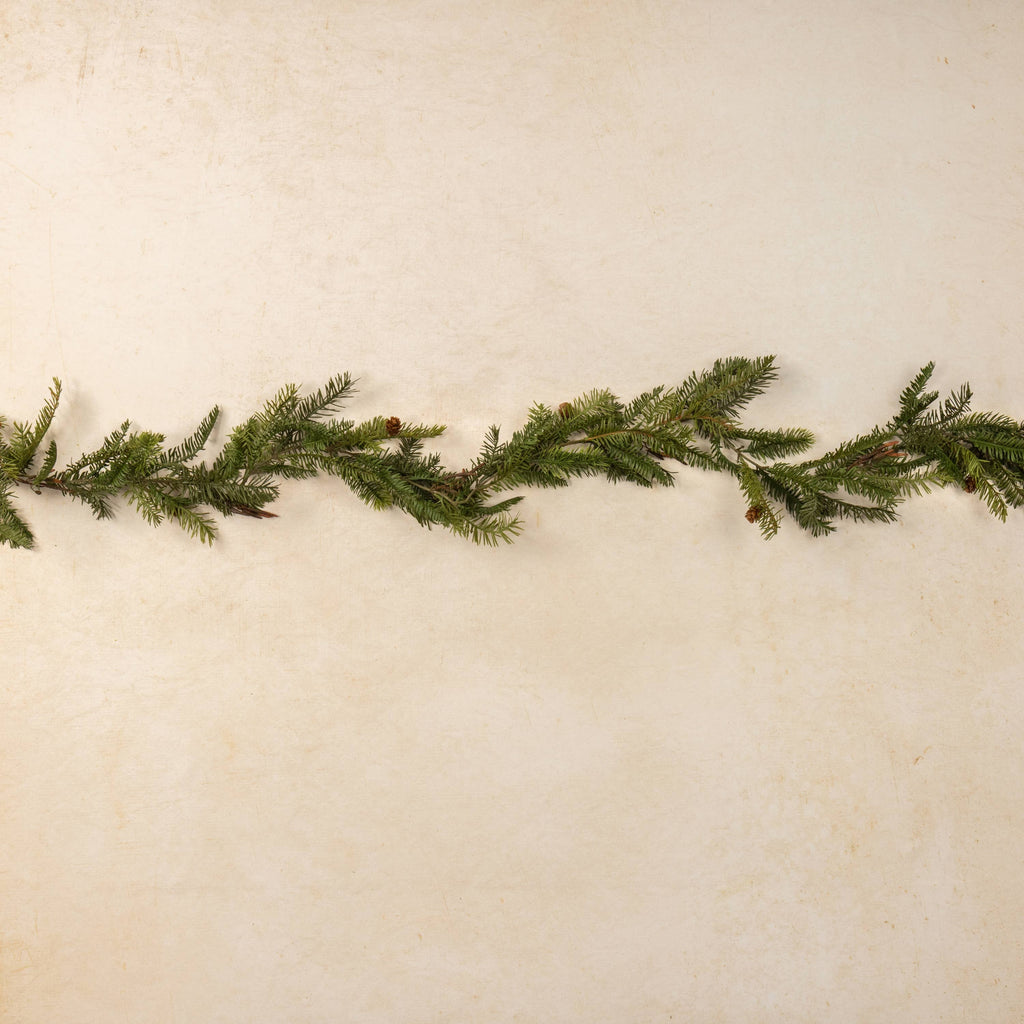 Green artificial Christmas garland on a textured beige background
