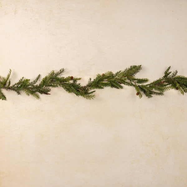 Green artificial Christmas garland on a textured beige background