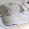 Beige cap with 'abode box' branding on a surface with branded paper and fabric.