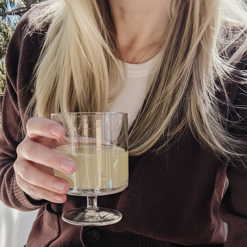 A person holding a clear acrylic stackable goblet filled with a beverage.