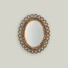 Decorative oval mirror with intricate gold frame on a light gray background