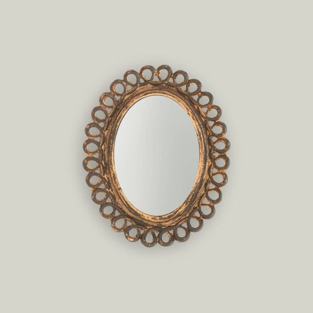 Decorative oval mirror with intricate gold frame on a light gray background