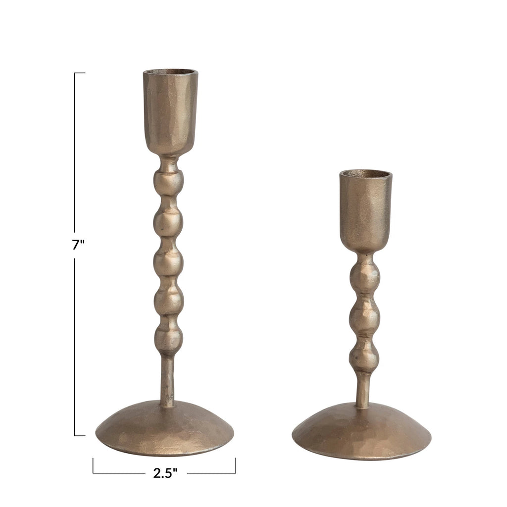 Two antique brass candle holders with dimensions indicated on a white background