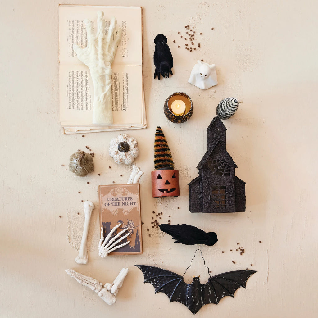 Halloween-themed decorations including a book, candles, and bats on a textured surface.