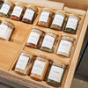 glass spice containers with bamboo lid in kitchen drawer with bamboo spice rack