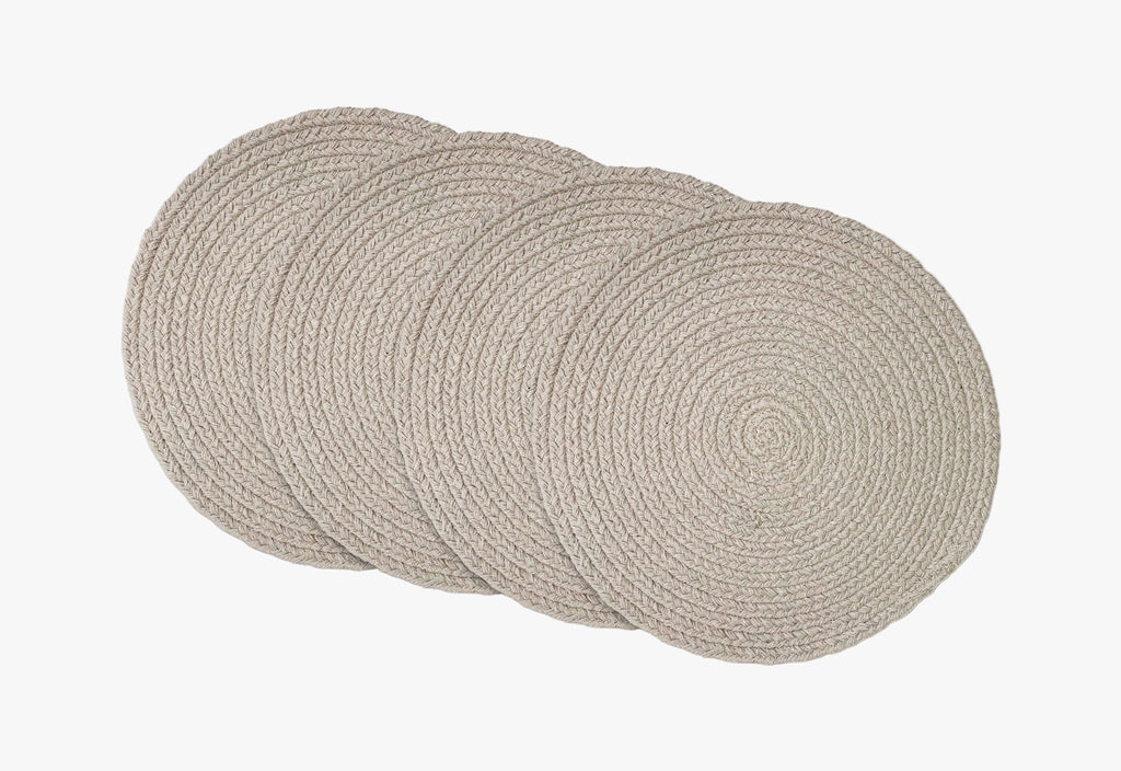 Set of four round woven placemats on a white background