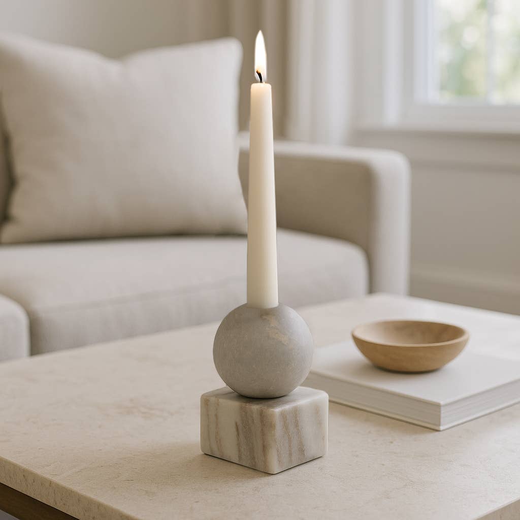 Candle in a decorative marble holder on a coffee table with a blurred living room background.  modern decor