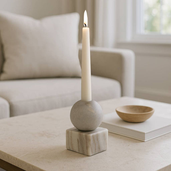 Candle in a decorative marble holder on a coffee table with a blurred living room background.  modern decor