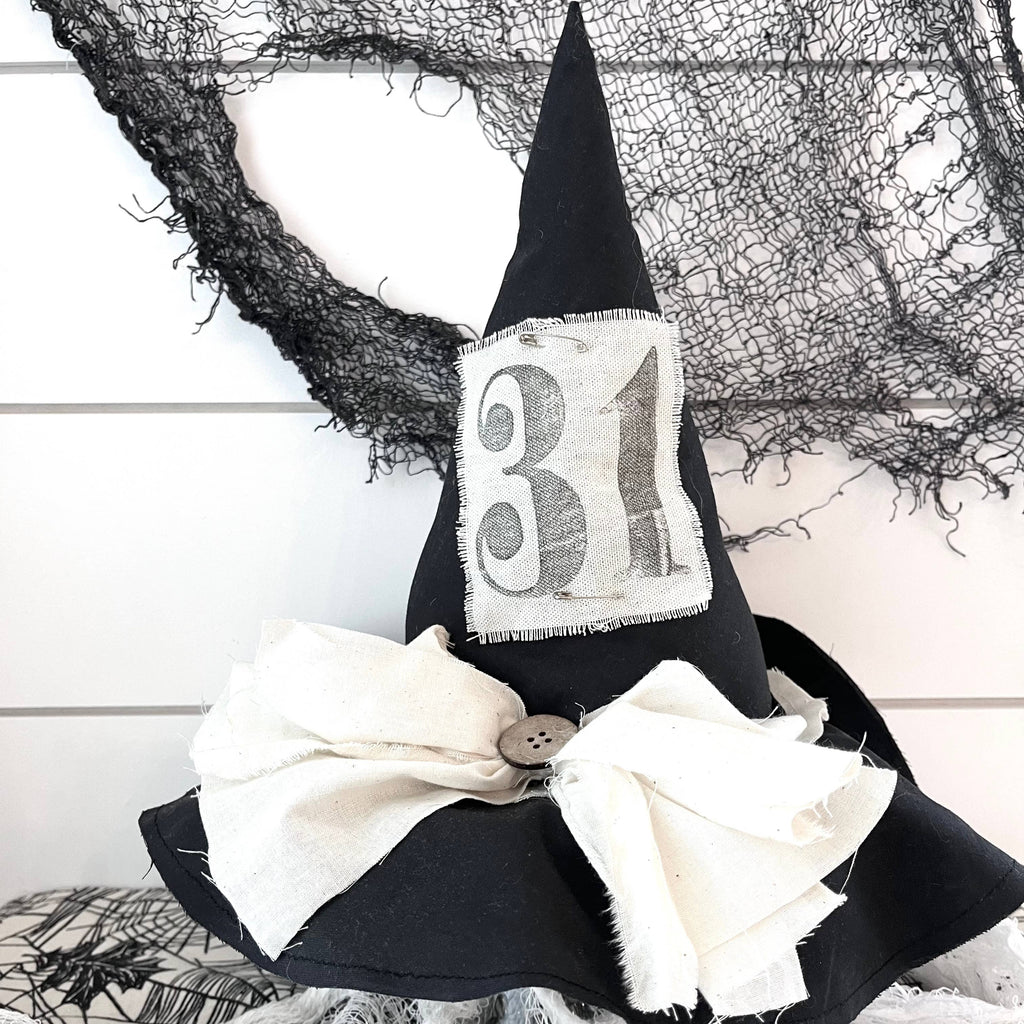 A handmade witch hat decor featuring a black hat with a white bow and a number 31 on the front, designed for Halloween decoration.