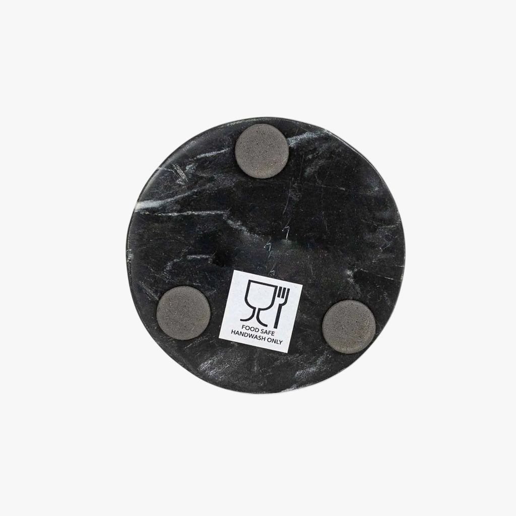 Black marble spoon rest with four gray circular pads on a white background