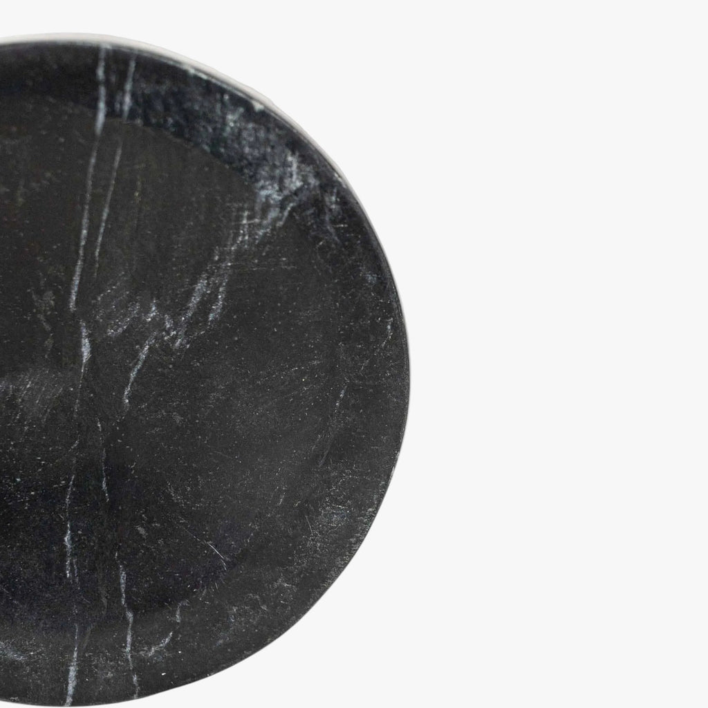 Round black marble spoon rest on a white background