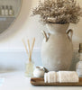 Decorative setup with a vase, towel, and diffuser on a shelf.