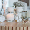 Candle labeled 'Weekend' with diffuser, mirror, and other decorative items on a wooden surface.