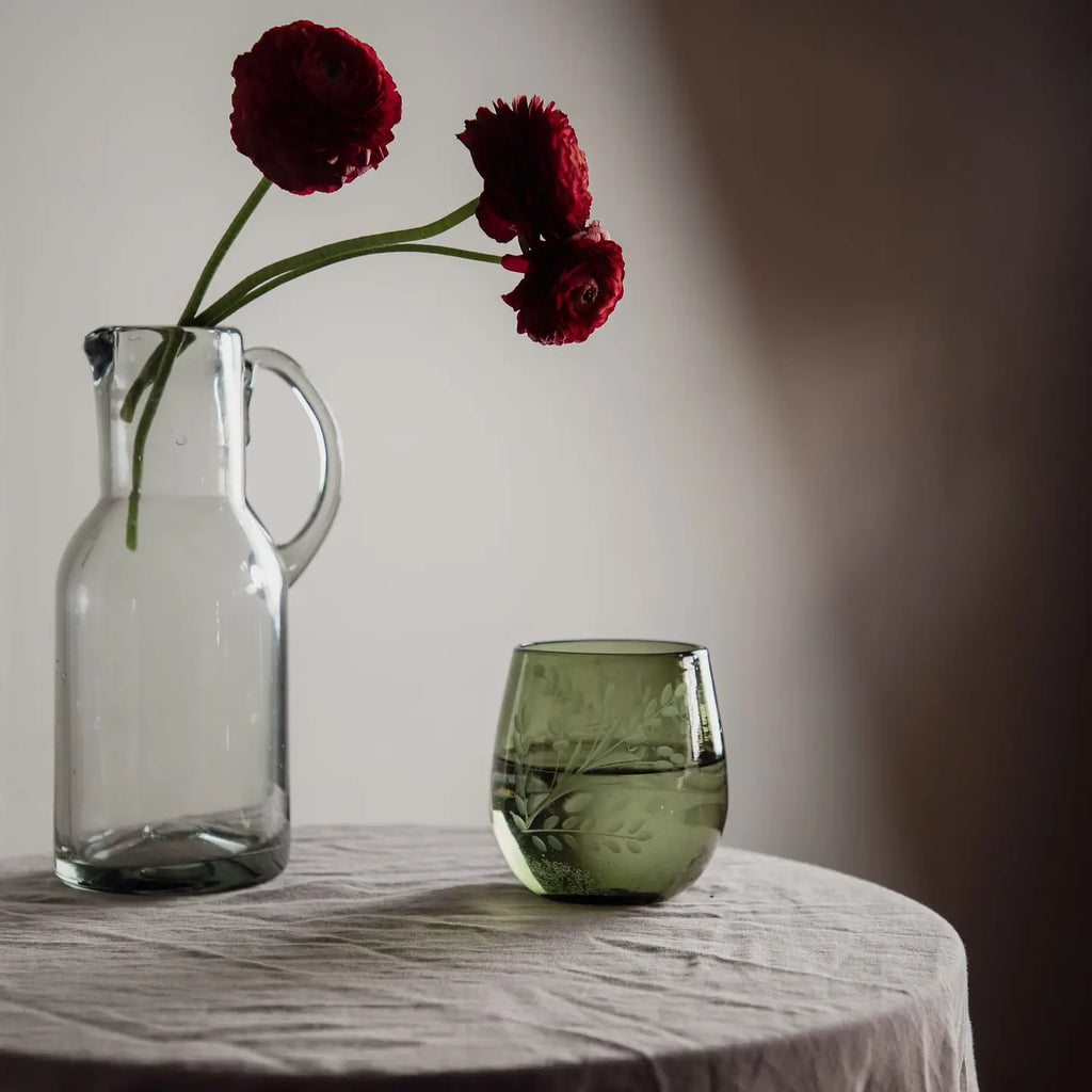 Blown Glass Pitcher used as a vase with flowers on table.