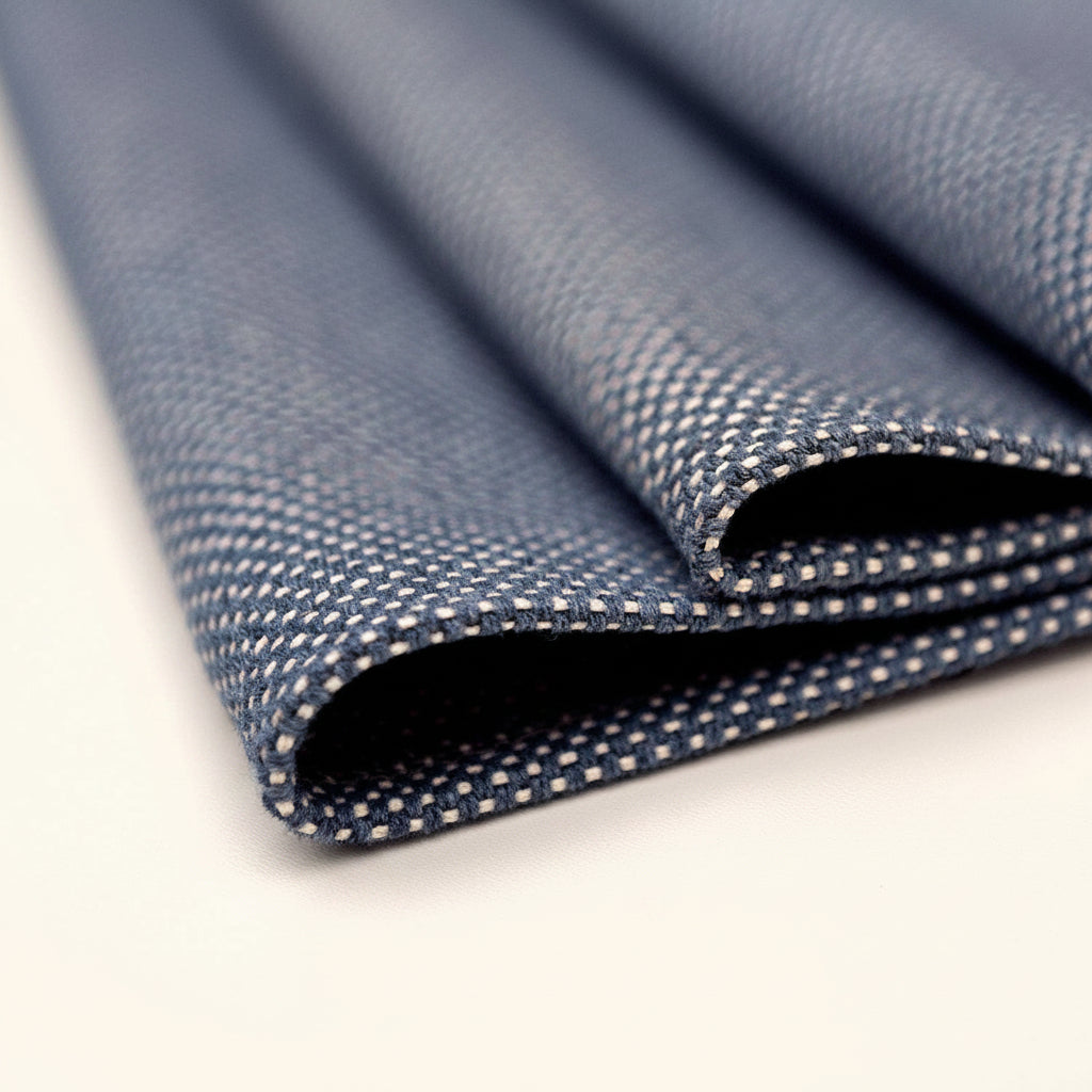 Close-up of blue textured placemat on a perforated white surface