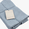 Folded blue textured placemat with a tag on a white background