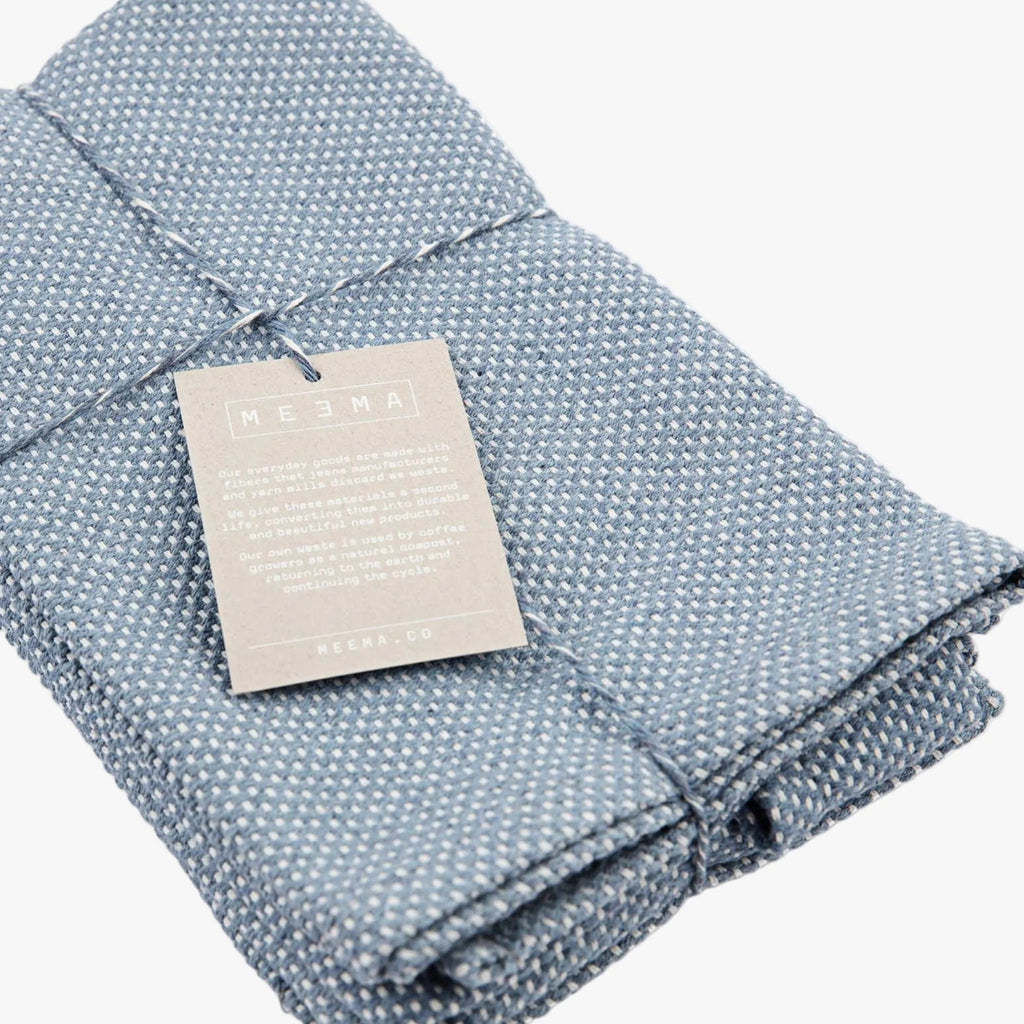 Folded blue textured placemat with a tag on a white background