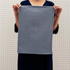 Woman holding a blue textured placemat against a light background