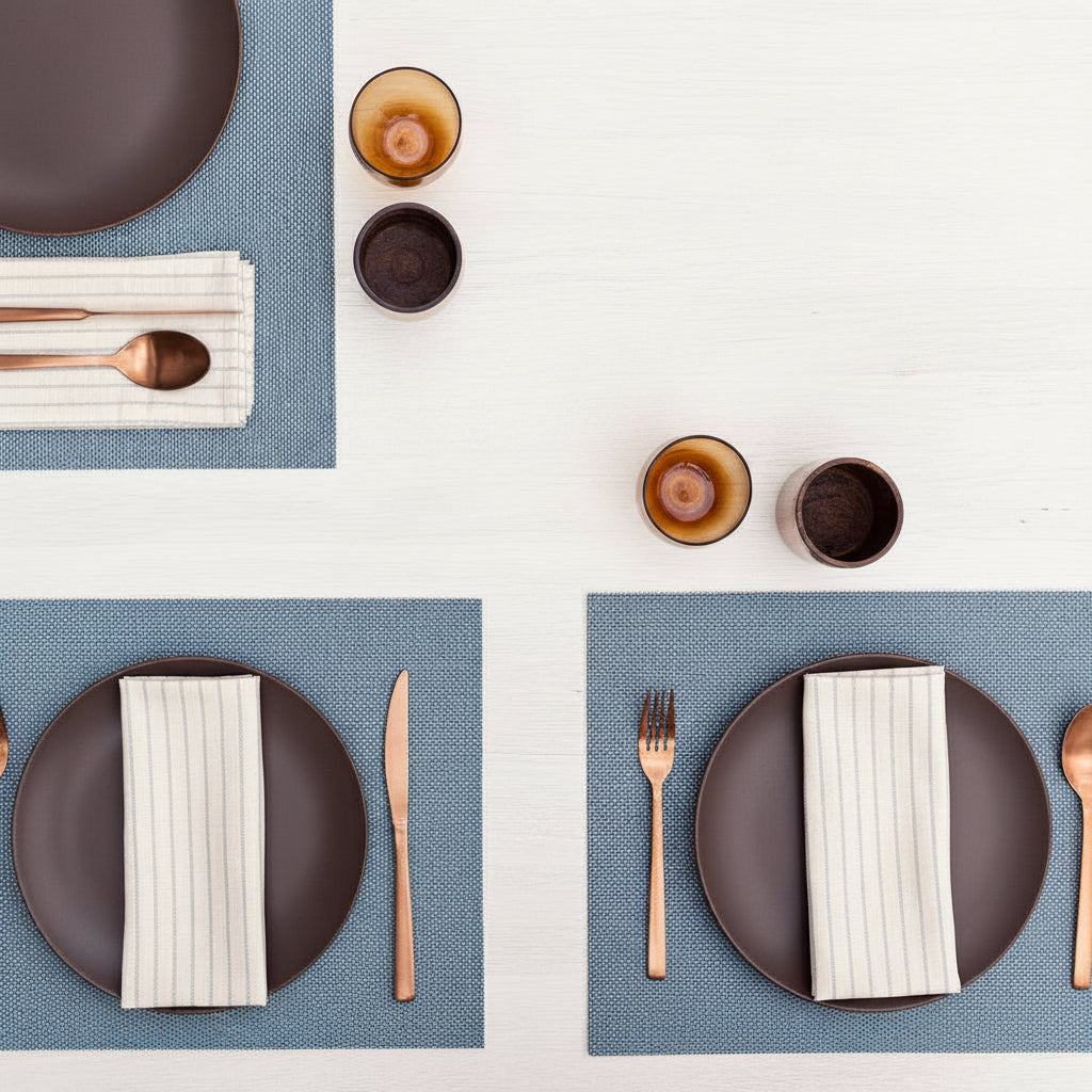 Table settings with blue cotton placemats, plates, cutlery, and decorative elements.