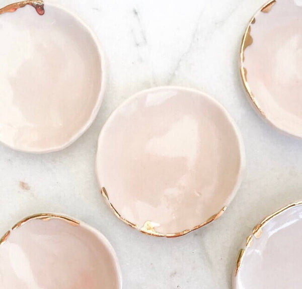 Set of pink ceramic ring dishes with gold rims on a marble surface