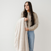 Woman holding a beige blanket against a plain background