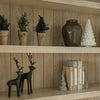 Decorative shelf with various holiday decor items including christmas trees, jars, and reindeer figurines against a wooden wall.