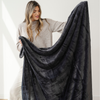 Woman holding a large dark gray blanket against a white background