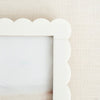 White scalloped picture frame on a beige background