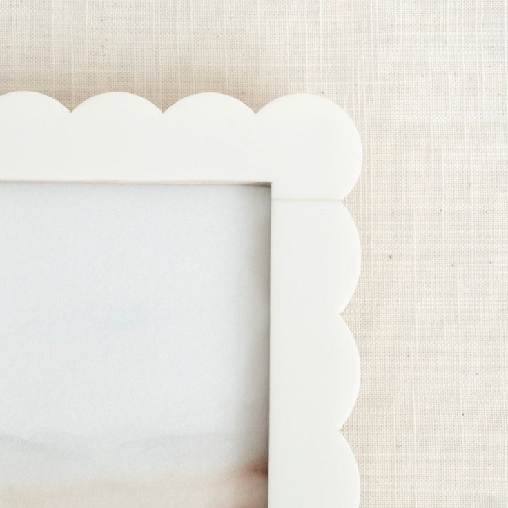 White scalloped picture frame on a beige background