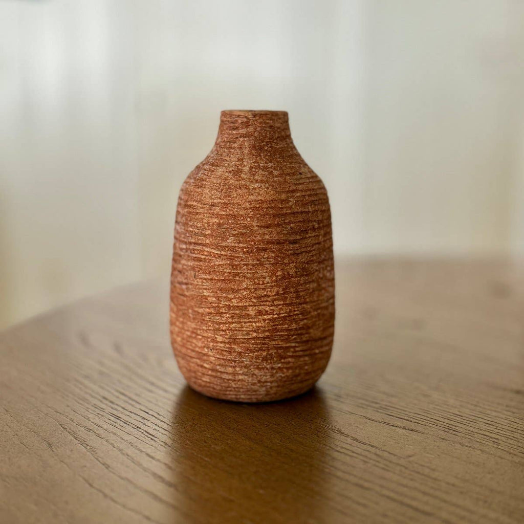 Textured brown vase on a wooden surface with a blurred background