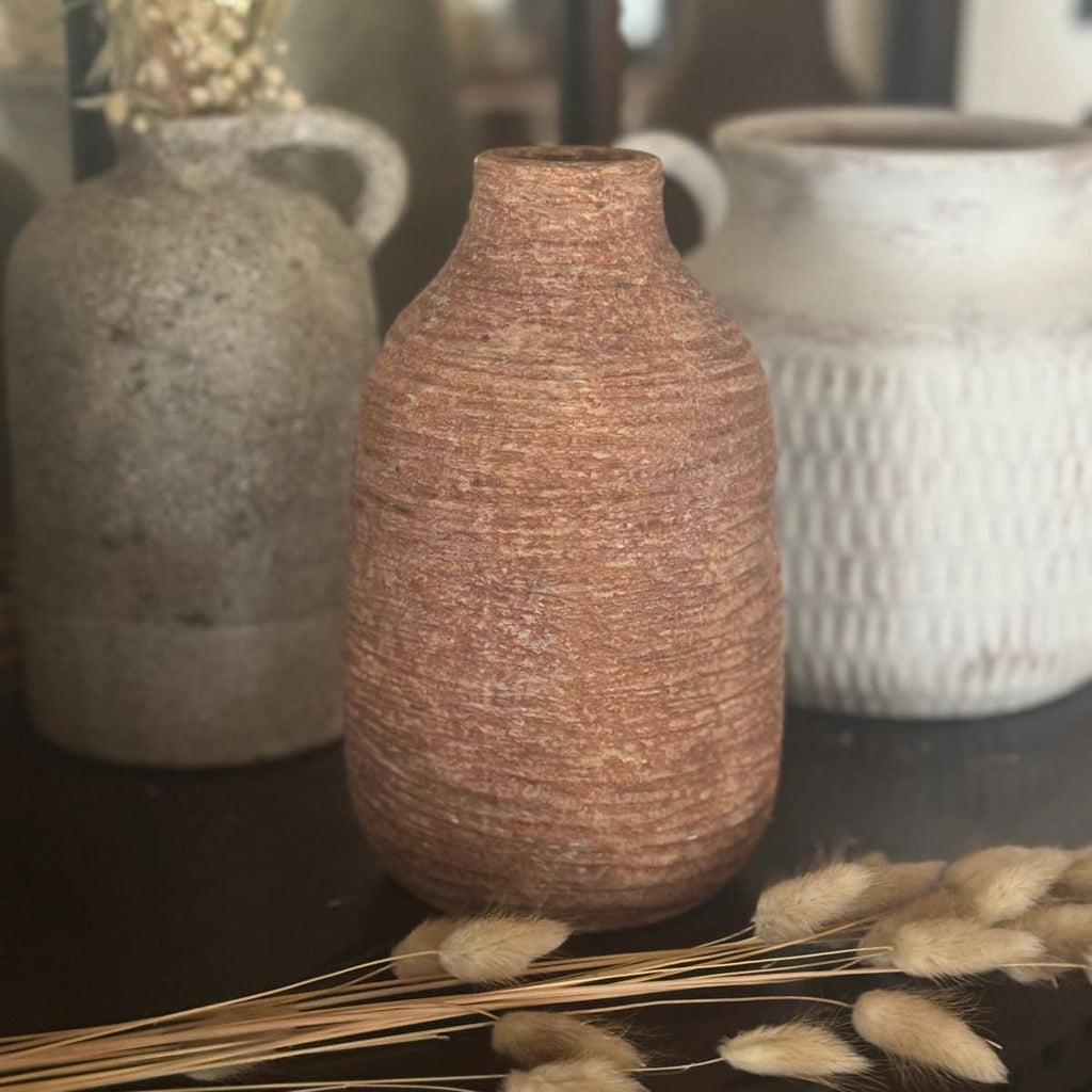 Textured ceramic vases on a dark surface with dried plants