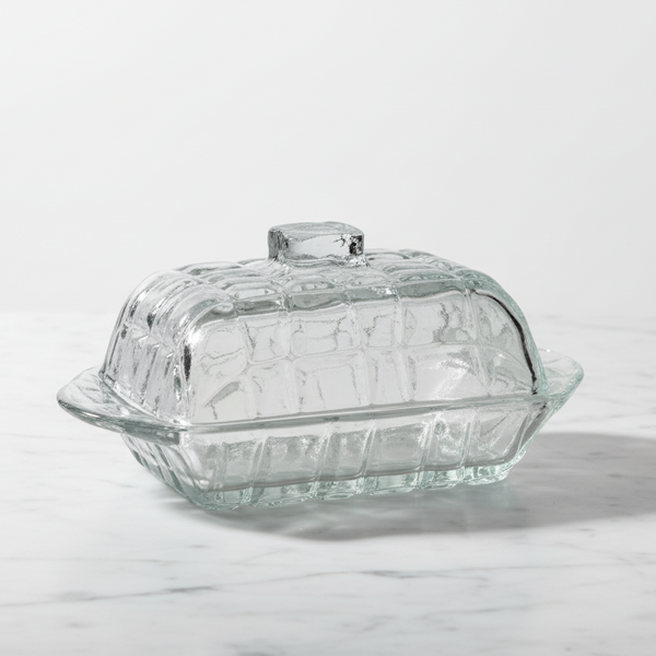 Clear glass butter dish with a lid on a white background