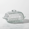 Clear glass butter dish with a lid on a white background