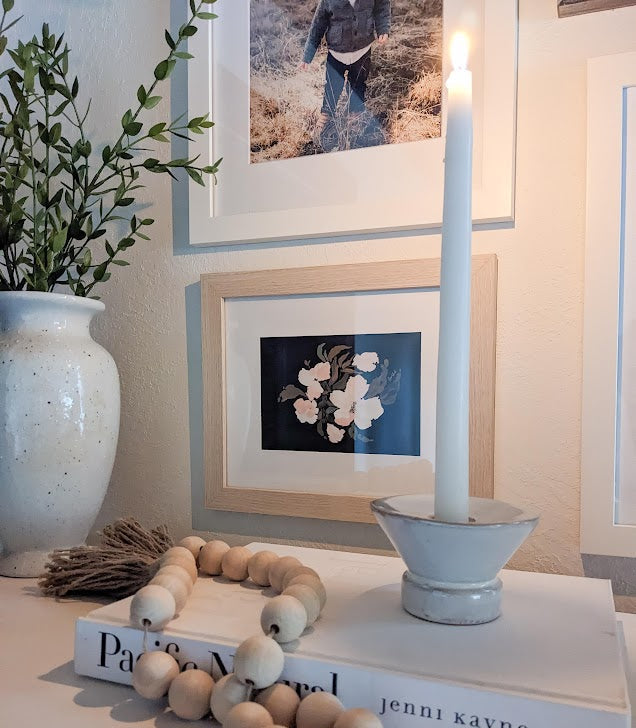 Decorative setup with candles, books, and a vase on a table.