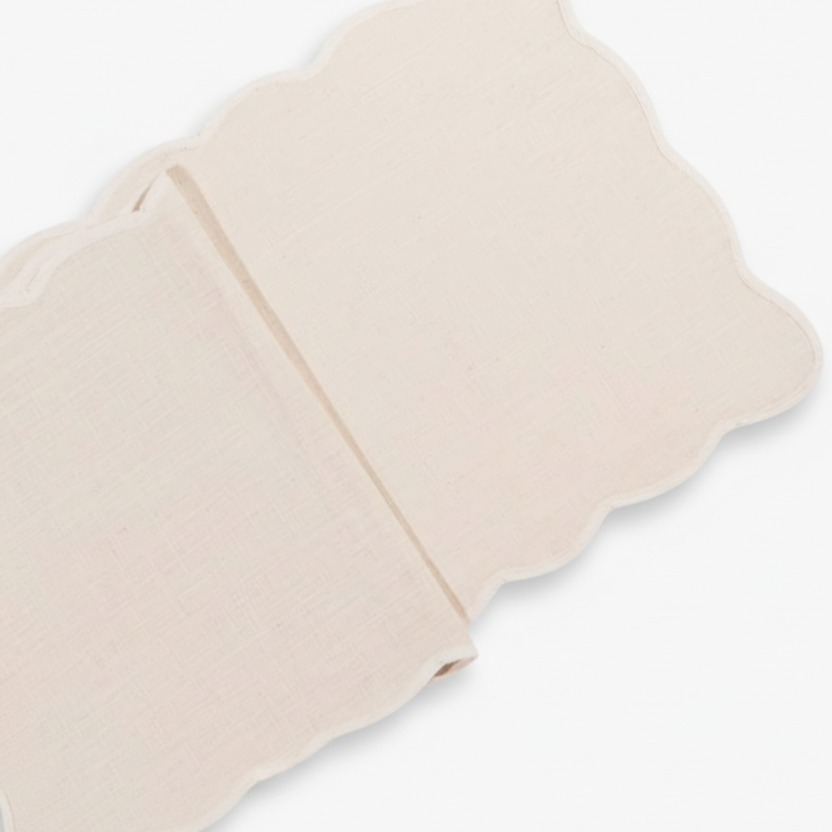 Cream table runner with scalloped edges on a white background