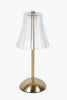 Gold table lamp with a clear glass shade on a white background