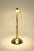 Table lamp with a clear glass shade and gold base on a neutral background