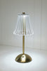 Small table lamp with pleated glass shade on a surface with books and shiplap in the background