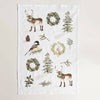 Decorative Christmas Tea towel with nature-themed designs including deer, trees, and wreaths on a white background.