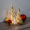 Decorative Christmas trees with lights and ornaments on a wooden surface