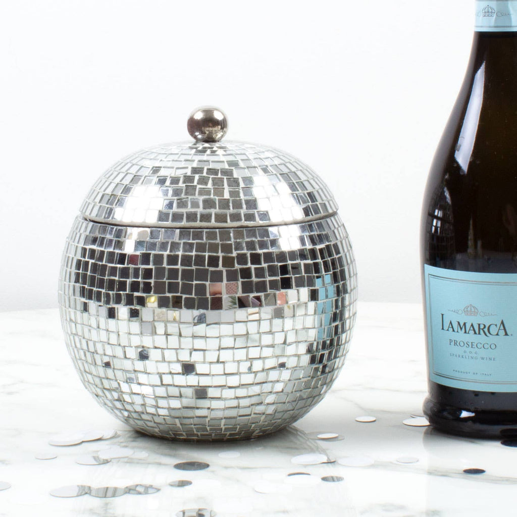 Silver disco ball ice bucket next to a bottle of La Marca Prosecco on a white surface.